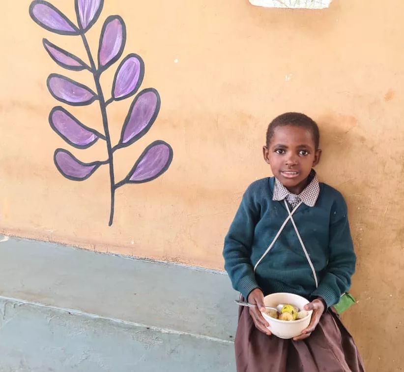 Child holding a bowl of food at school